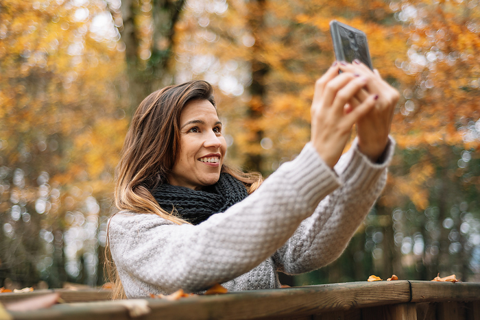 Beautiful young happy woman taking selfie with smartphone in autumn park. Season, technology and people concept. Beautiful young happy woman taking selfie with smartphone in autumn park. Season, technology and people concept.