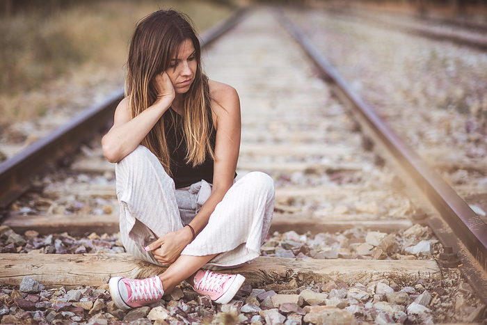 Portrait Of a Young Sad woman, Sitting pensive Outdoors On The Railway track. Portrait Of a Young Sad woman, Sitting pensive Outdoors On The Railway track.