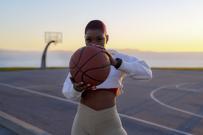 033 Portrait of mid adult woman holding basketball at sunset