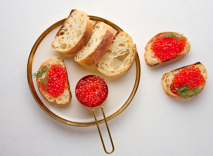 Sandwiches with red caviar and bread in a round plate on a white table, top view Sandwiches with red caviar and bread in a round plate on a white table, top view