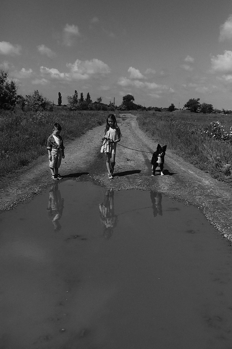 Country road with a large puddle and children with dog