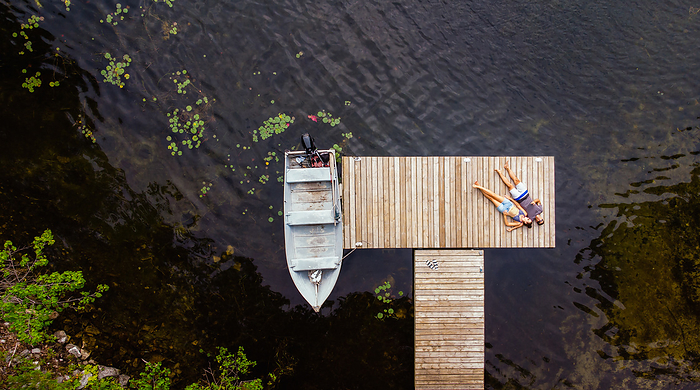 Overhead aerial image of couple laying on a dock together.