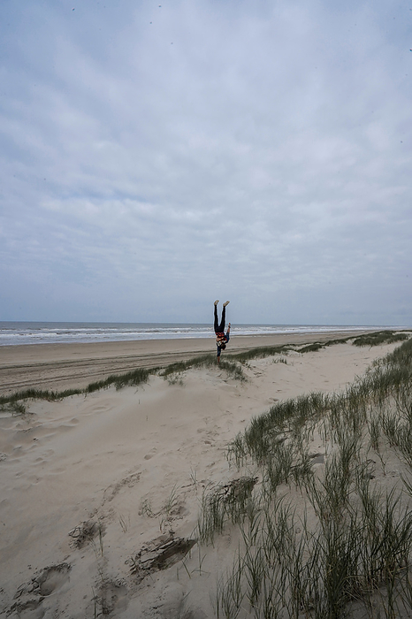 A man doing a Handstand on a beach near the sea, Netherlands, Europe