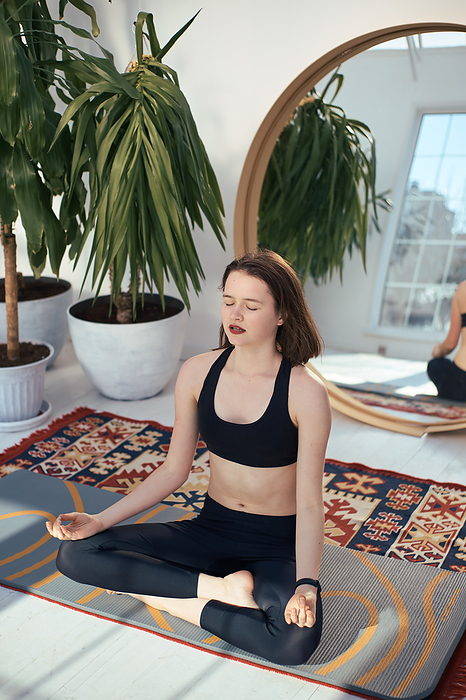 Young woman practices lotus position at home