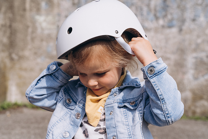 Stylish cute preschooler girl puts a protective helmet on her head