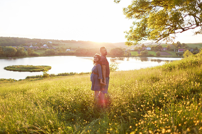 man and woman stand embracing in field of flowers in rays of sun