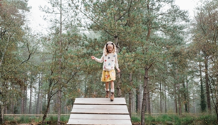 girl walking down a wooden ramp in the forest in autumn