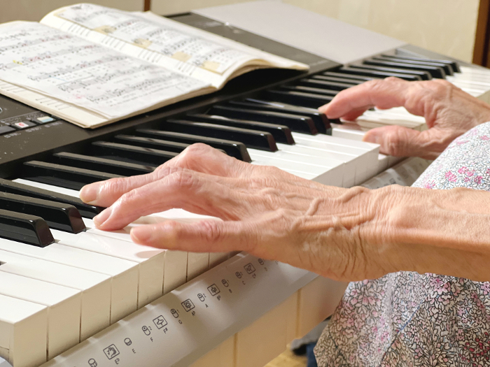 Elderly woman playing keyboard, close-up of her hand