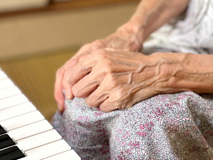Elderly woman clasping her hands on her lap in front of the keyboard