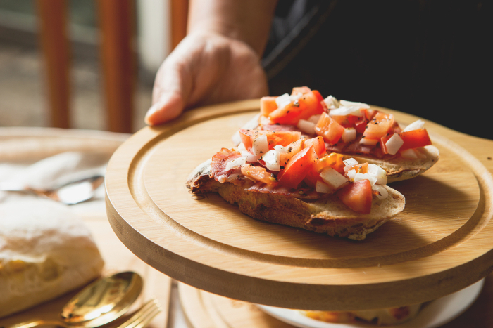 Man's hand holding open tomato sandwich tartine