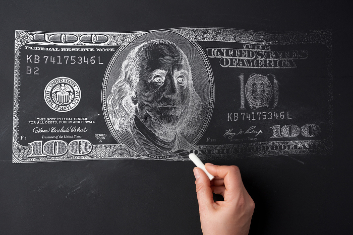 A woman s hand draws a dollar on a black chalk board. The concept of inflation, rising prices A woman s hand draws a dollar on a black chalk board. The concept of inflation, rising prices