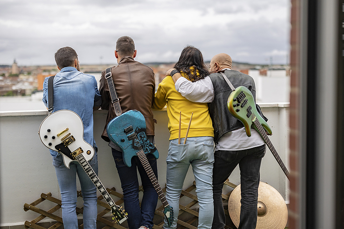 Rock musicians standing together with electric guitars on rooftop