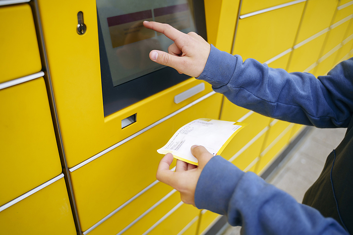 Boy with ticket entering details on parcel locker screen
