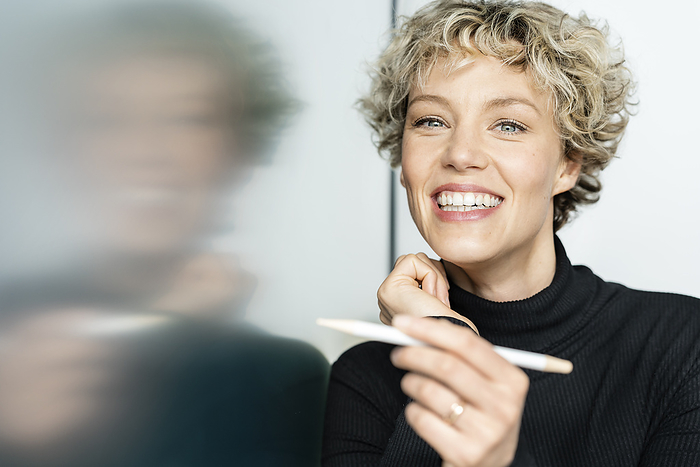 Happy businesswoman with digitized pen pointing on interactive whiteboard