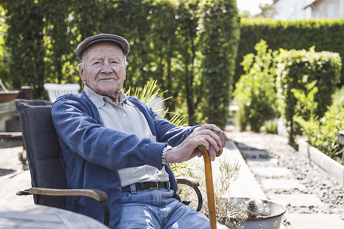 Smiling senior man wearing beret sitting in armchair