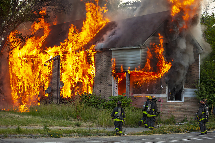 Firefighters attending house fire Abandoned house burning from a suspected arson attack with firefighters at the scene. Photographed in Detroit, Michigan, USA., by JIM WEST SCIENCE PHOTO LIBRARY