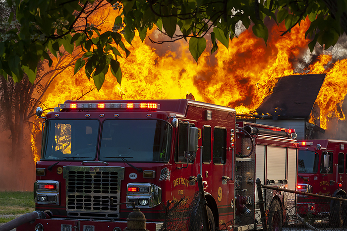 Firefighters attending house fire Abandoned house burning from a suspected arson attack with the fire department at the scene. Photographed in Detroit, Michigan, USA., by JIM WEST SCIENCE PHOTO LIBRARY