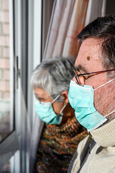 senior couple, with protective face masks, at home looking through the window. Concept of coronavirus quarantine stay home and social distancing. Lockdown people. elderly and retired lifestyle. Senior Couple, with Protective Face Mask, at Home Looking Through the Window. Concept of Coronavirus Quarantine Stay Home and Social Distancing. Lockdown People. Elderly and Retired Lifestyle., by Zoonar DAVID HERRAEZ