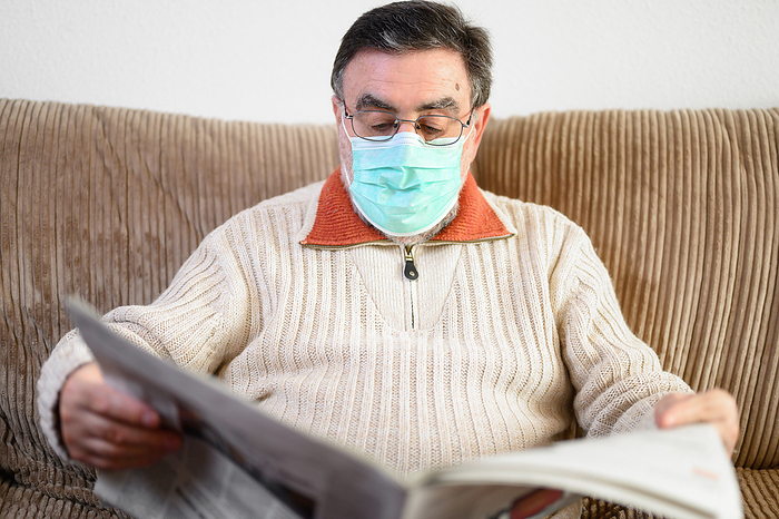 Elderly man reading newspaper during coronavirus epidemic quarantine. Elderly Man Reading Newspaper During Coronavirus Epidemic Quartantine., by Zoonar DAVID HERRAEZ