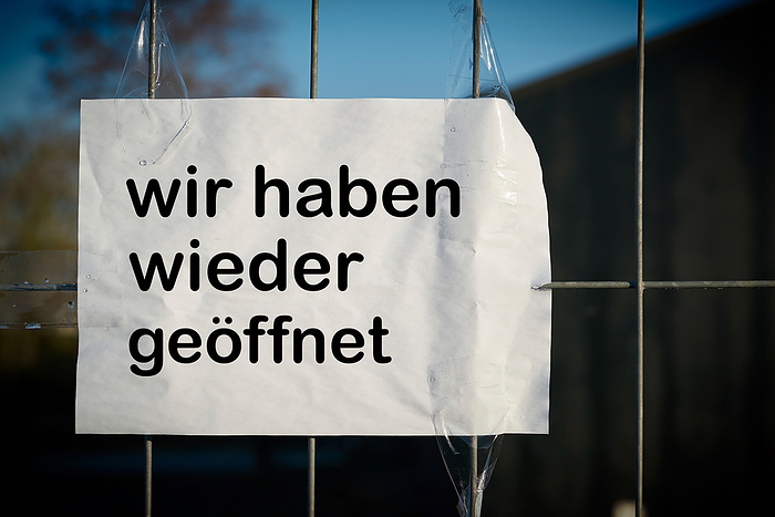 Sign on a fence with the words  Sign on a fence with the words we have opened again, by Zoonar Heiko Kueverl