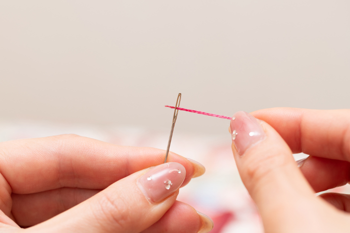Woman's hand threading a needle