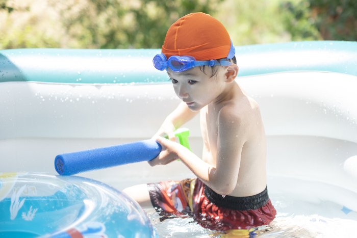 A 5-year-old playing in a plastic pool in the garden