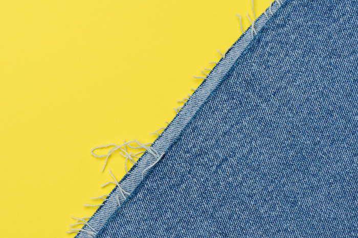 Torn edges of blue jeans on a yellow background Torn edges of blue jeans on a yellow background
