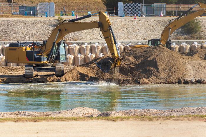 Hydraulic excavator scooping sediment from river bottom