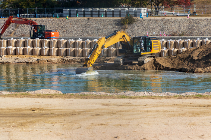 Hydraulic excavator digging up sediment from the river bottom