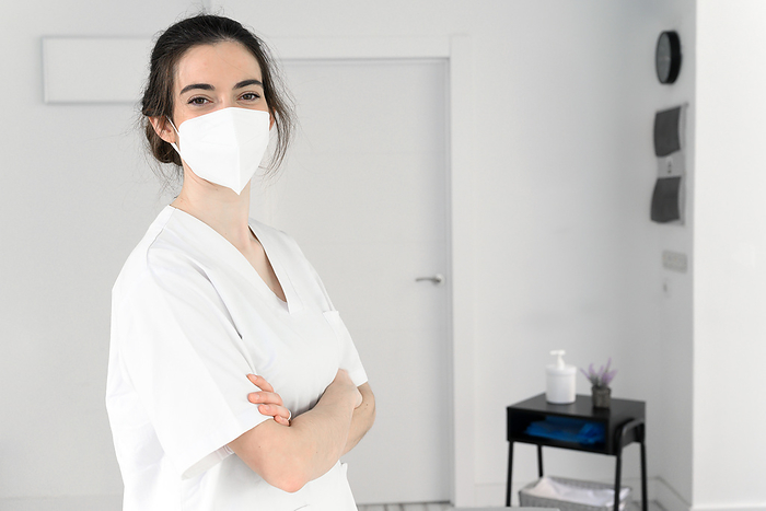 Friendly female physiotherapist posing in modern clinic wearing protective face mask during coronavirus pandemic Friendly Female Physiotherapist Posing in Modern Clinic Wearing Protective Face Mask During Coronavirus Pandemic, by Zoonar DAVID HERRAEZ