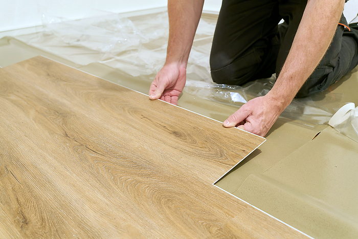 Craftsman renovating an apartment and laying a click vinyl floor covering Craftsman renovating an apartment and laying a click vinyl floor covering, by Zoonar Heiko Kueverl