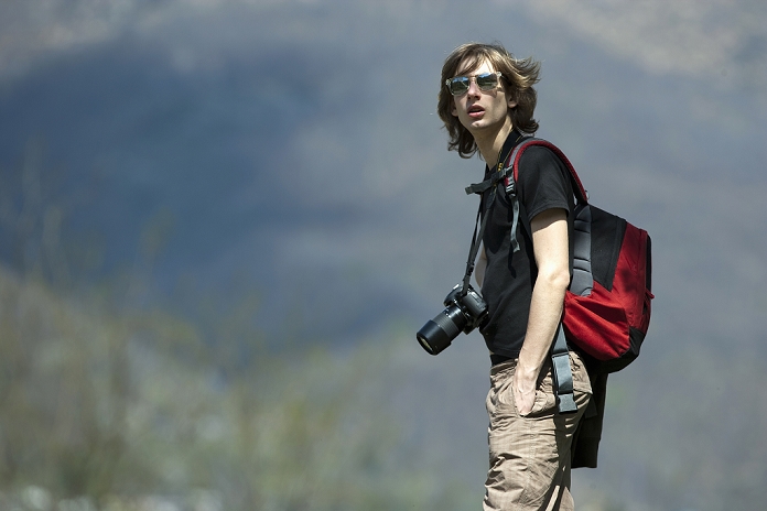 Teenage boy hiking with camera