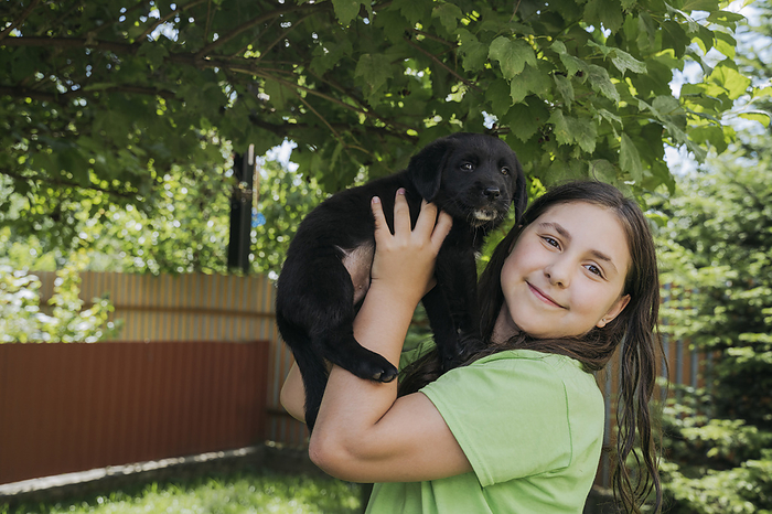 Smiling girl holding puppy in back yard