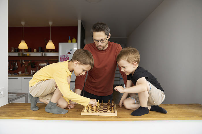 Father with sons playing chess at home