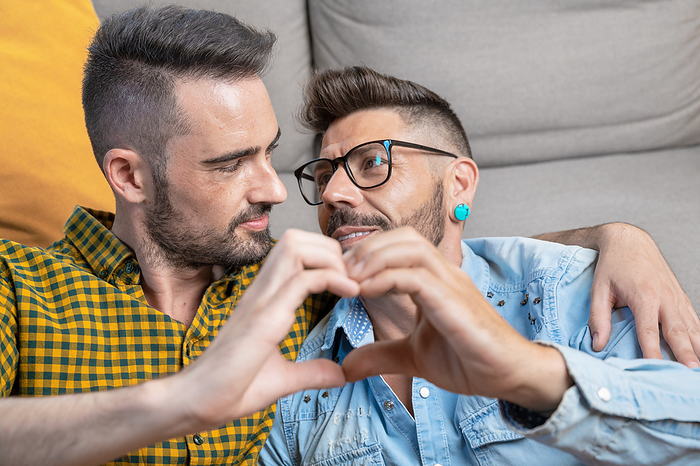 Young gay couple smiling confident doing heart symbol with hands at home Young gay couple smiling confident doing heart symbol with hands at home, by Zoonar DAVID HERRAEZ
