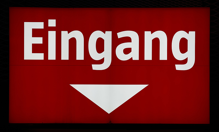 illuminated red sign at the entrance to a store in Germany. Translation: entrance illuminated red sign at the entrance to a store in Germany. Translation: entrance, by Zoonar Heiko Kueverl