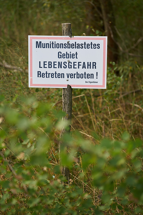 Prohibition sign in a forest in Germany. Translation: ammunition contaminated area, danger to life Prohibition sign in a forest in Germany. Translation: ammunition contaminated area, danger to life, by Zoonar HEIKO KUEVERL