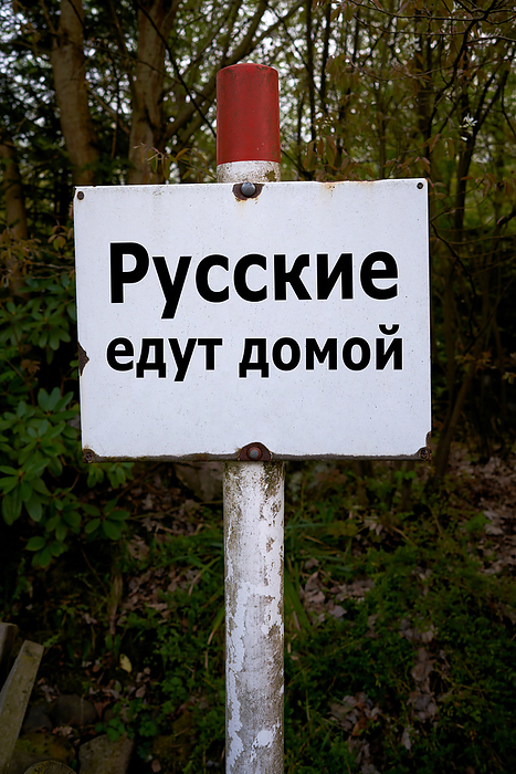Sign in Russian language in a forest with the inscription Russians go home Sign in Russian language in a forest with the inscription Russians go home, by Zoonar Heiko Kueverl