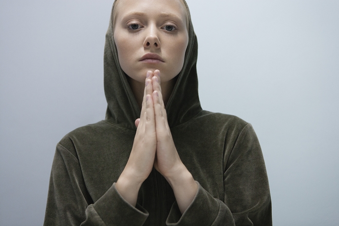 Young woman with hands clasped in prayer, portrait