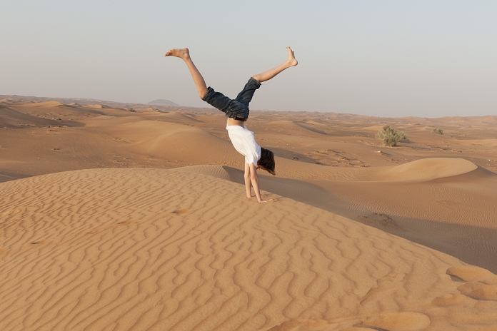 Teenage boy doing handstand in desert