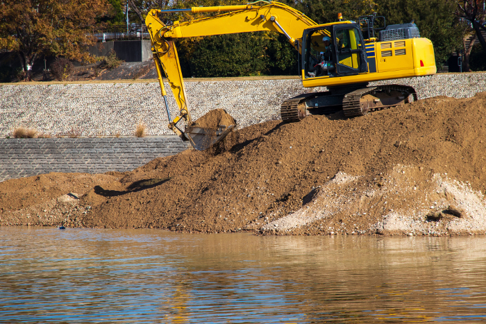 Hydraulic excavator digging for earth and sand on riverbank