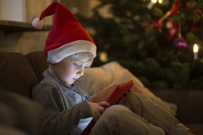 Christmas Children Boy in Santa hat using tablet computer