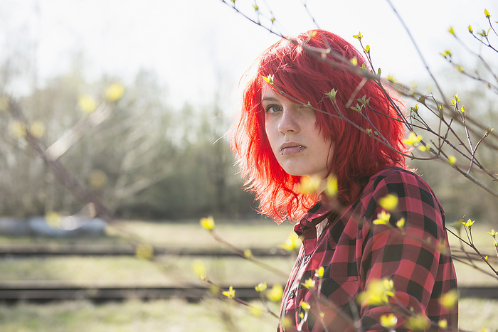 Shy teenage Punk girl fashion dyed bright red hair, by Cavan Images / Edith Drentwett