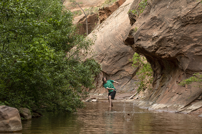 Young man skips stones in creek, by Cavan Images / Mark Lipczynski