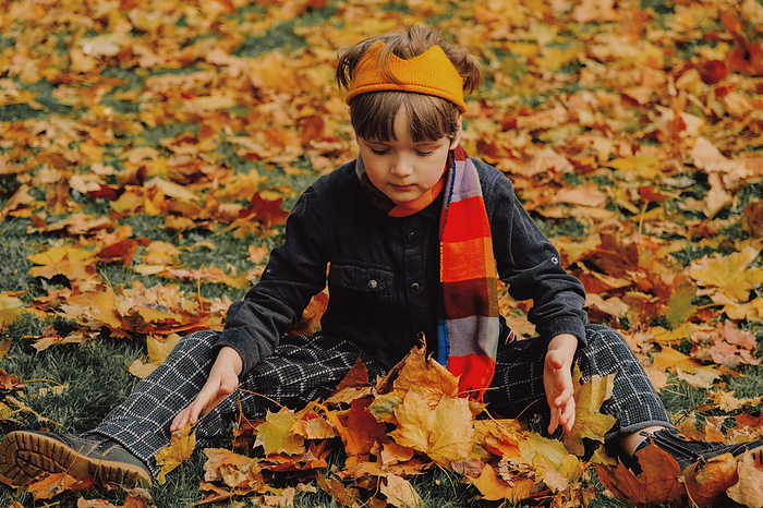 Autumn Boy Portrait In Fall Yellow Leaves in Park Outdoor, by Cavan Images / Darya Kisialiova