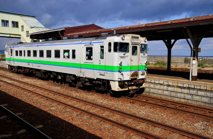Kiha 40 Series stopping at Mori Station on the Hakodate Main Line, with a view of the sea at Uchiura Bay...