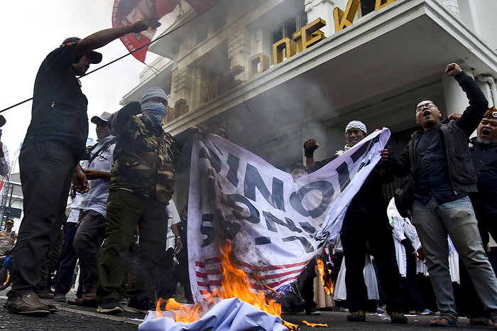 Thousands of people at Pro Palestinian Demonstration in West Java Indonesia People burn a poster picturing the Israeli and USA flags on a street as they gather for a pro Palestinian demonstration in Bandung, West Java,Indonesia on October 21, 2023. Thousands of people attend the demonstration to condemn against the genocide of the government of Israel and express solidarity with the Palestinian people.