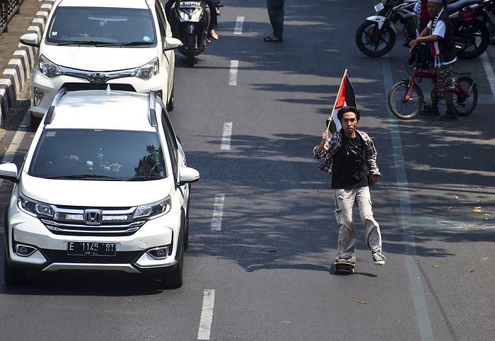 Thousands of people at Pro Palestinian Demonstration in West Java Indonesia A man using a skateboard holds a Palestinian flag as people gather for a pro Palestinian demonstration in Bandung, West Java,Indonesia on October 21, 2023. Thousands of people attend the demonstration to condemn against the genocide of the government of Israel and express solidarity with the Palestinian people.