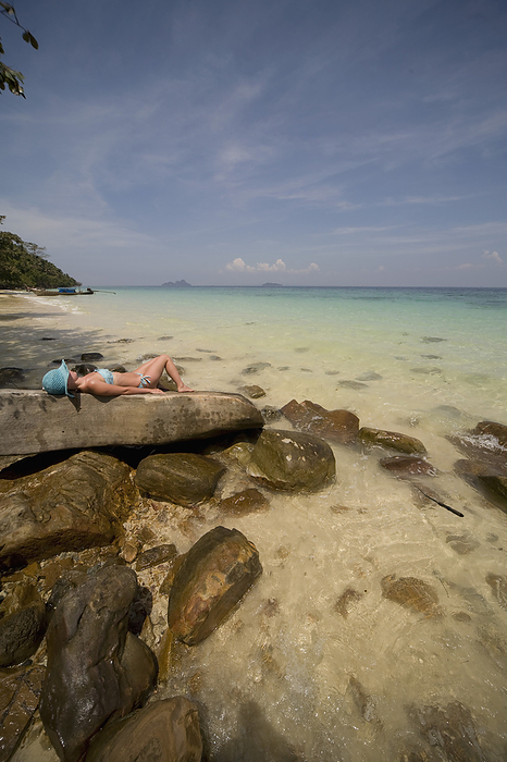 Young woman lying on rocks sunbathing and relaxing, Koh Phi Phi, Thailand, by Ableimages