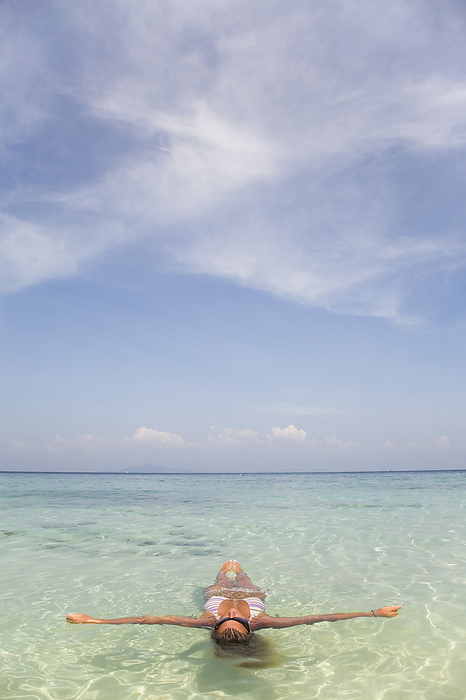 Young woman floating in crystal clear sea water with arms wide open, Koh Phi Phi, Thailand, by Ableimages